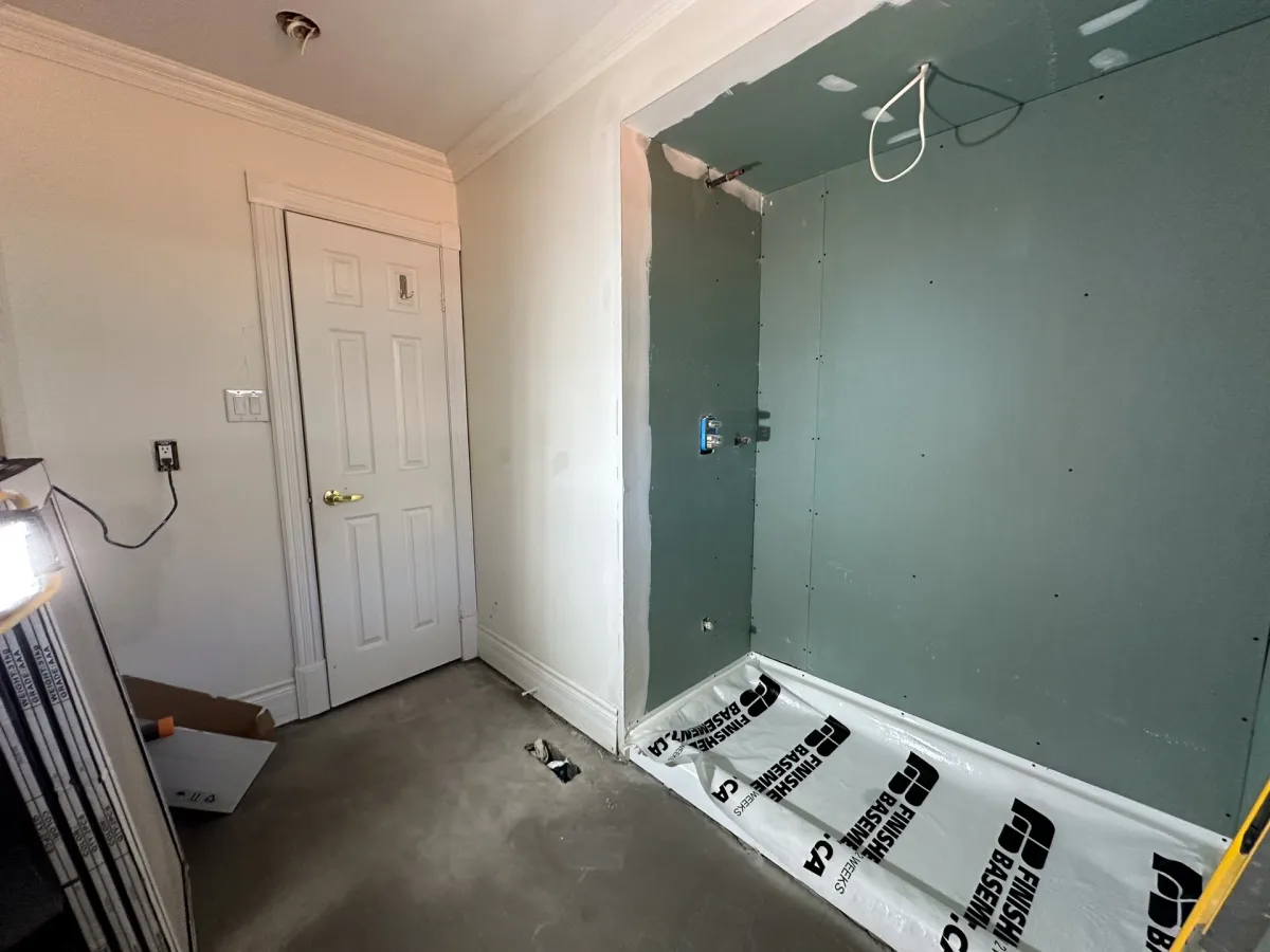 Mid-build: the shower walls sheeted in cement board, the new floor protected under paper and the vanity wall primed
