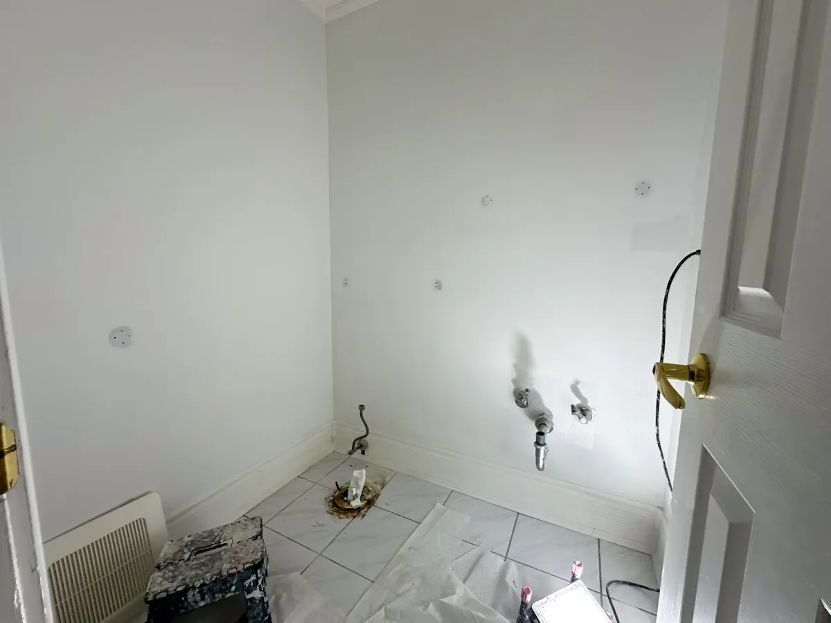 Part-way through: the old fixtures out, the walls patched and skimmed, the supply lines capped and the floor protected
