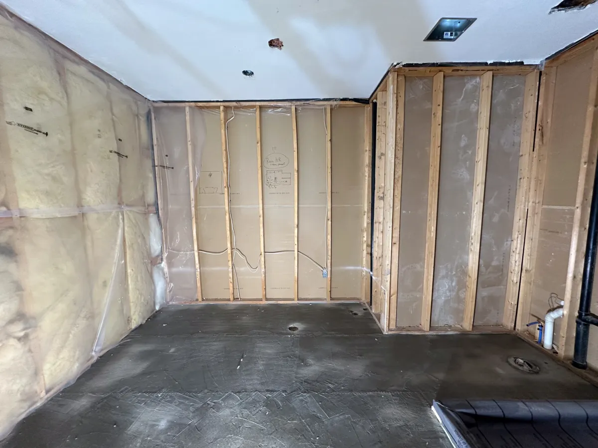 The room taken to the studs, the insulation open and the concrete floor bare