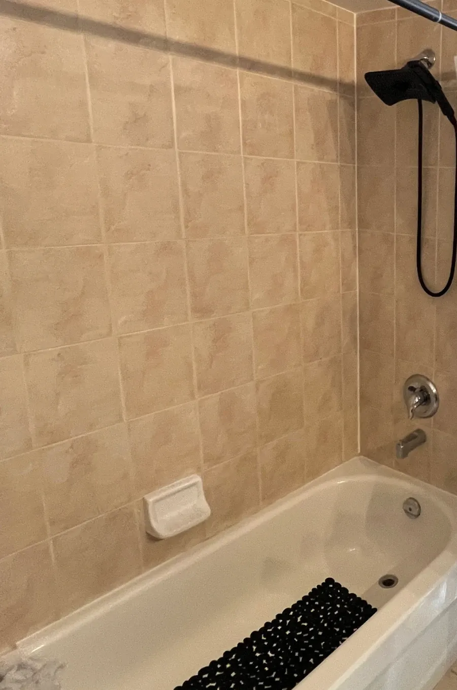 Before: the old alcove tub with a beige ceramic surround, a hand shower on a slide bar and a curtain
