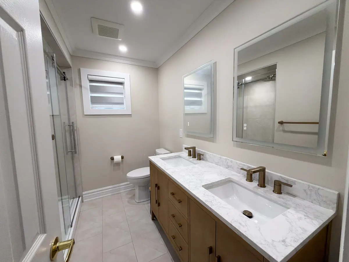 Four-piece bathroom with a wood double vanity, marble-look quartz top, brass taps and a sliding-glass shower