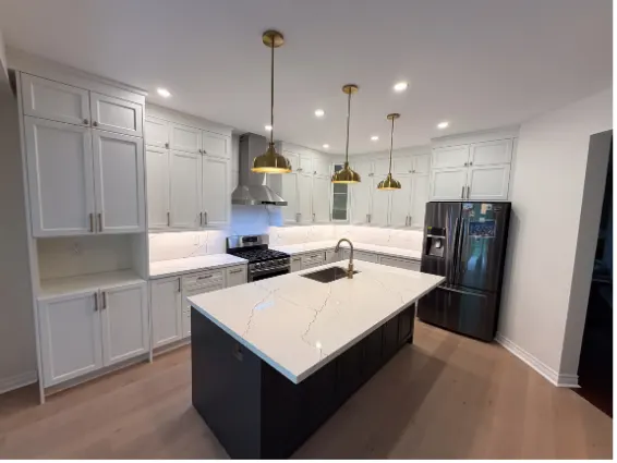 White kitchen with a dark quartz-topped island and brass pendant lights