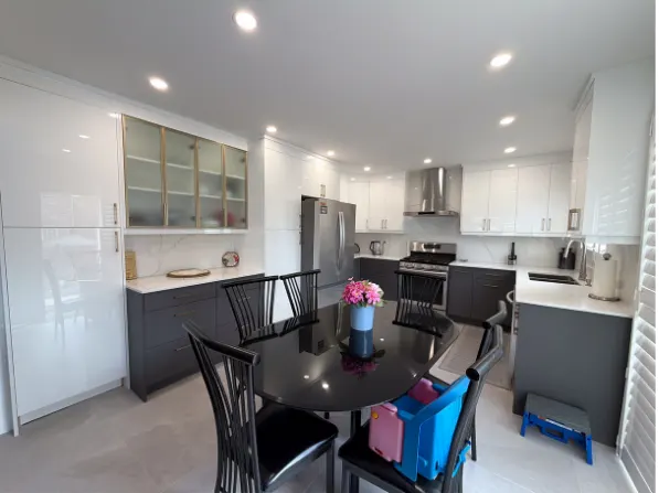High-gloss white kitchen with graphite base cabinets and a dining table