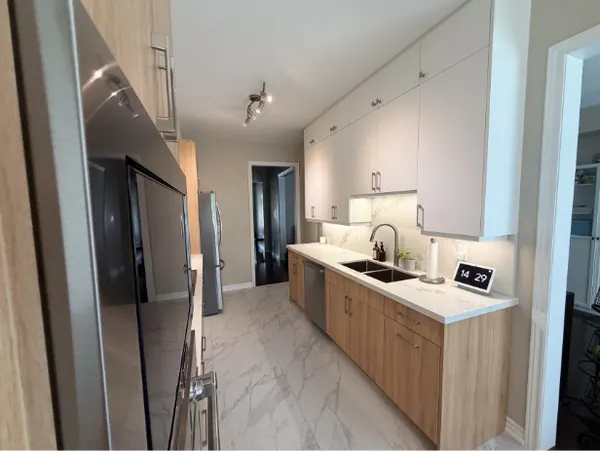Light wood and white galley kitchen with quartz counters and a marble-look floor