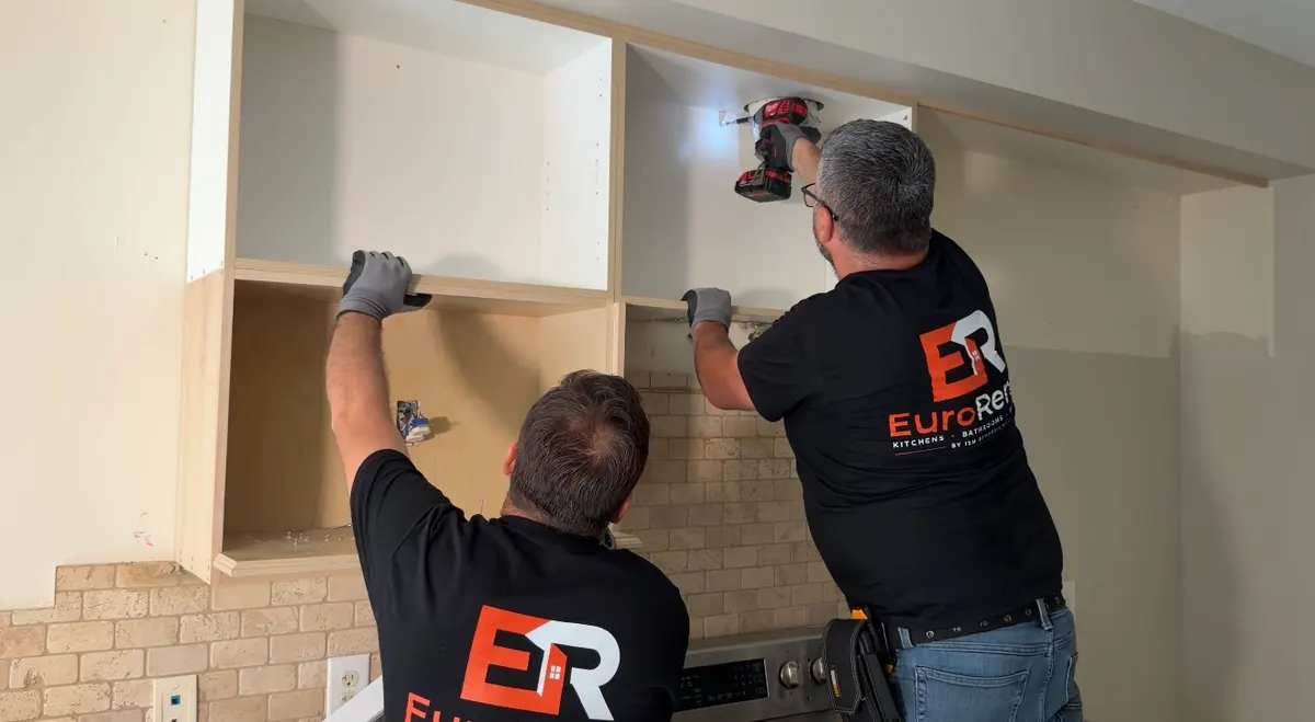 Two Euro Renovations installers fitting upper cabinets