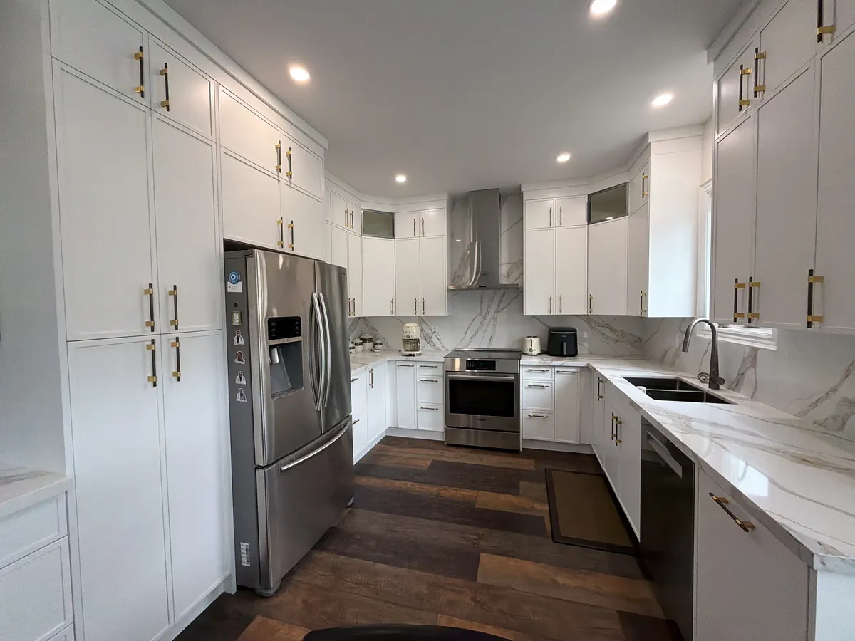 White U-shaped kitchen with dark hardwood floor and stainless appliances