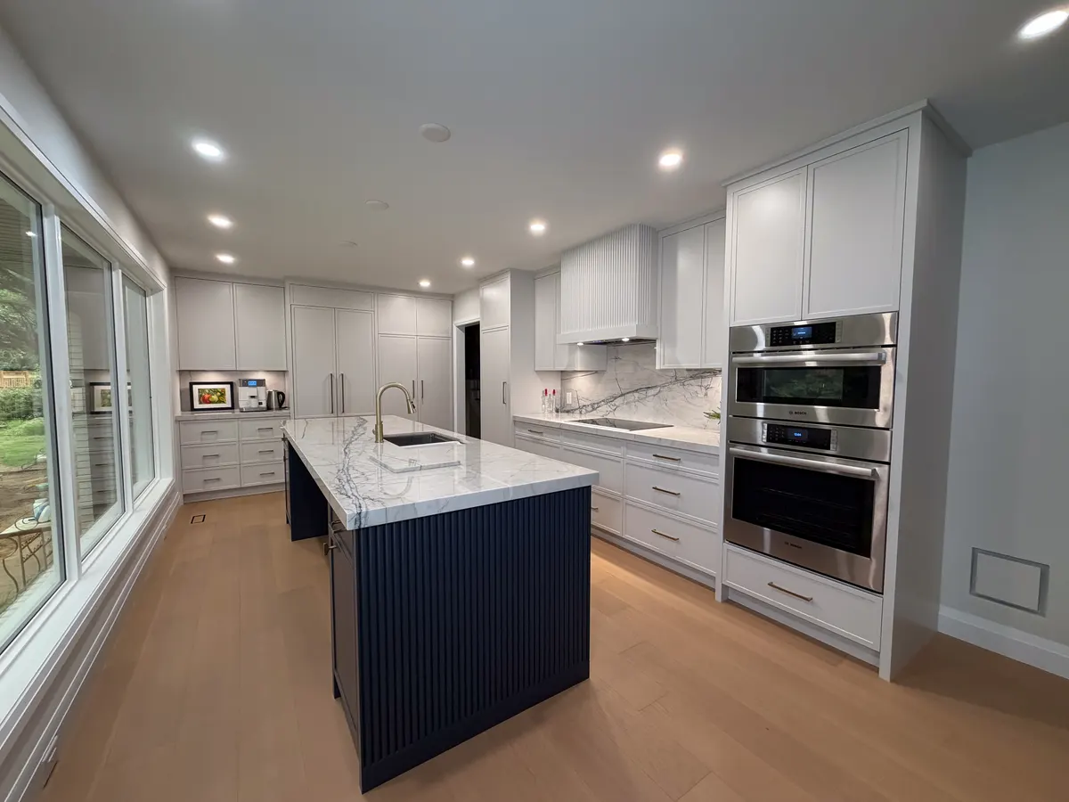 Kitchen with a fluted navy island, marble waterfall counter and light oak floor