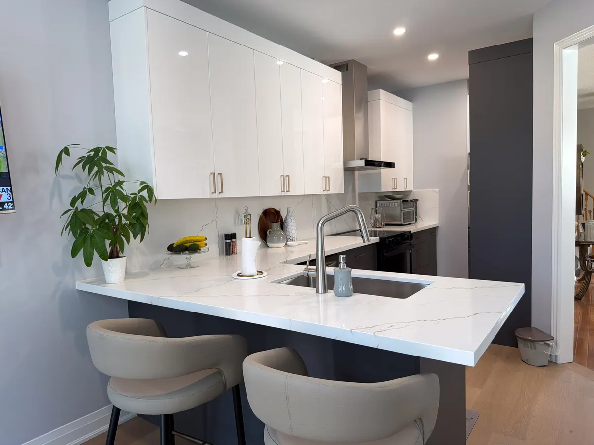 White kitchen with a quartz peninsula and upholstered bar stools