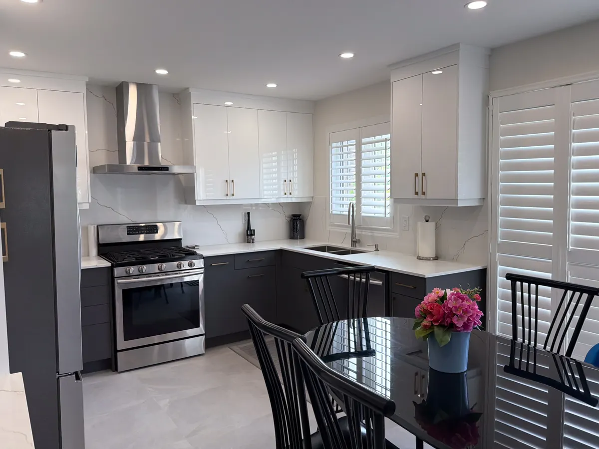Kitchen with white uppers, dark base cabinets and a stainless hood