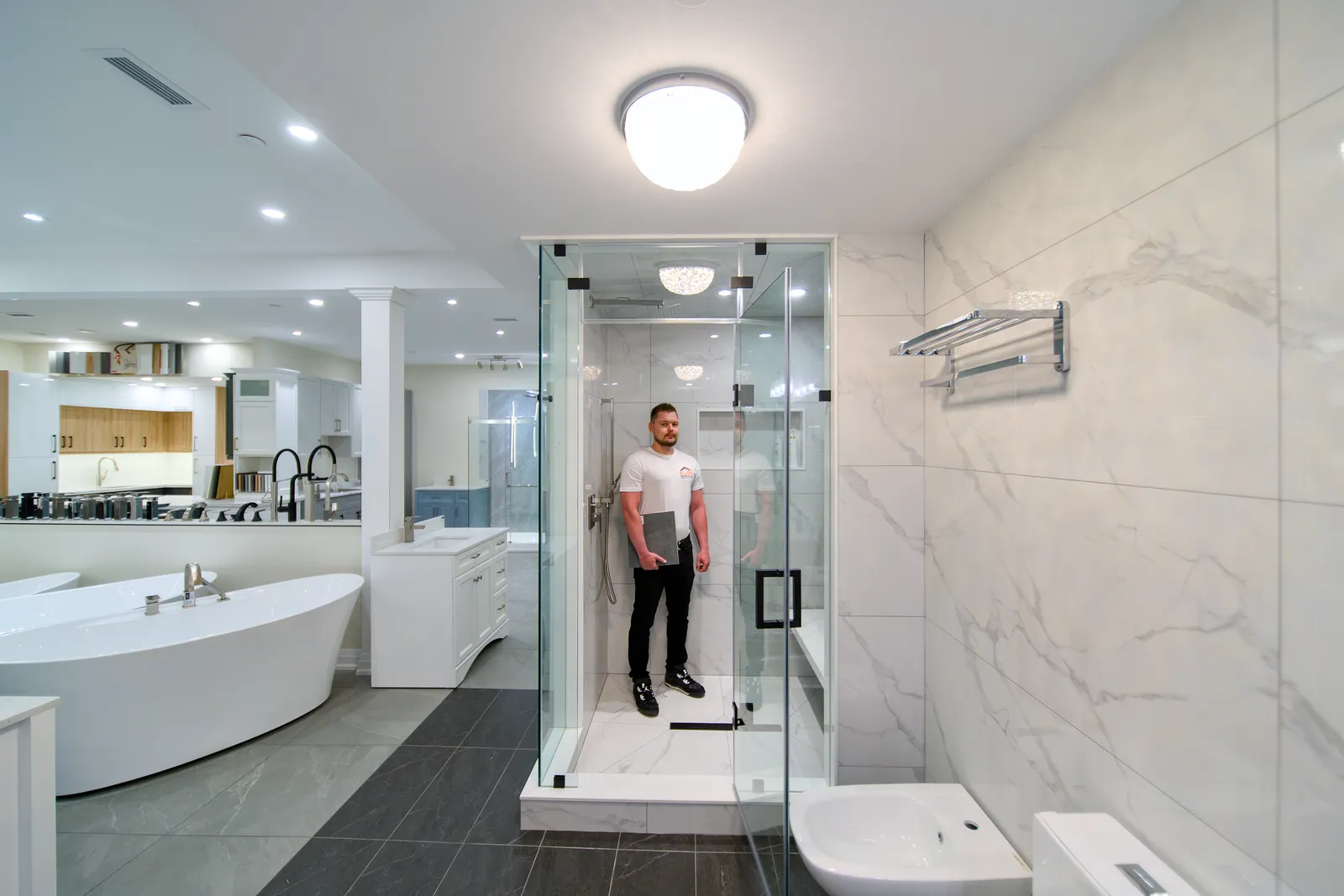 Bathroom display in the Mississauga showroom with two full-size walk-in showers and a freestanding tub
